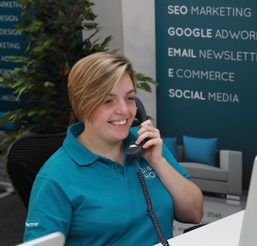 Digital House team member on the phone Digital House team member in a teal polo shirt taking a call at reception